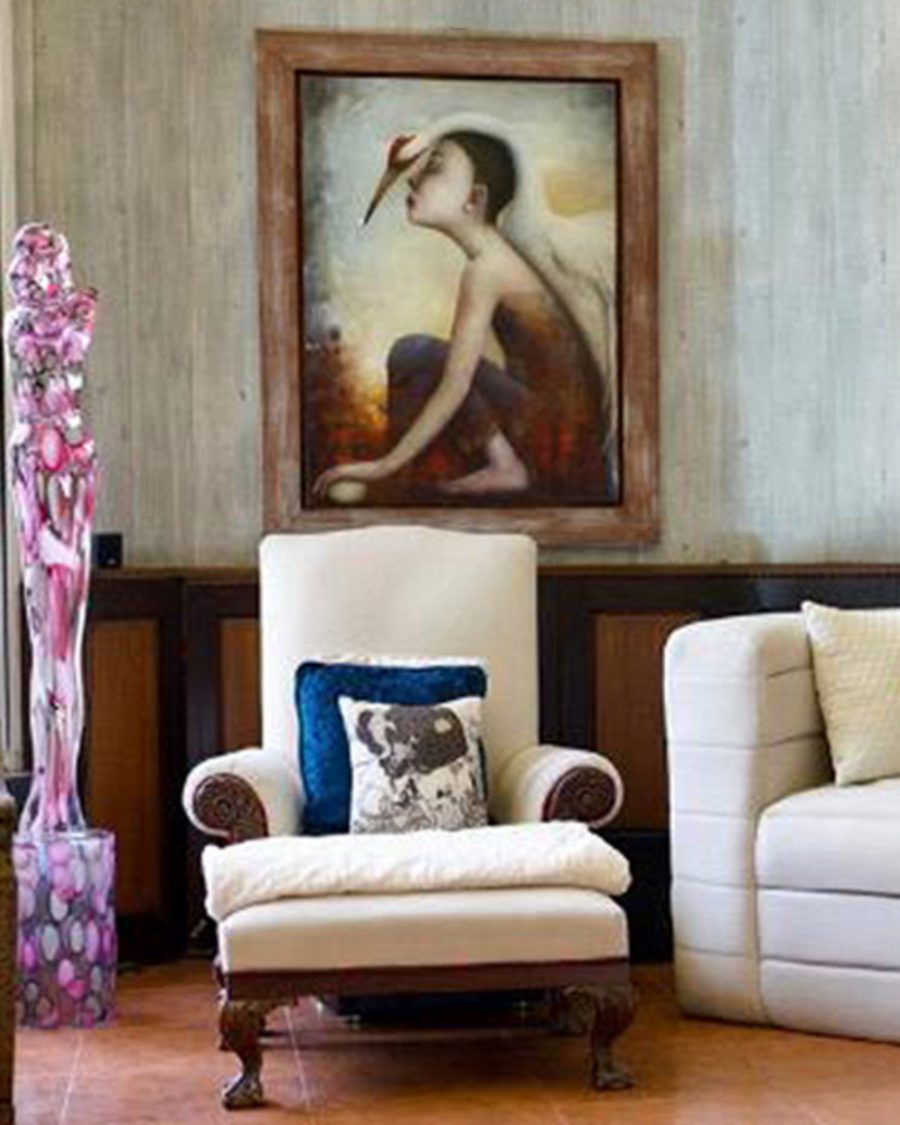 A large orange canvas above a leather Chesterfield sofa