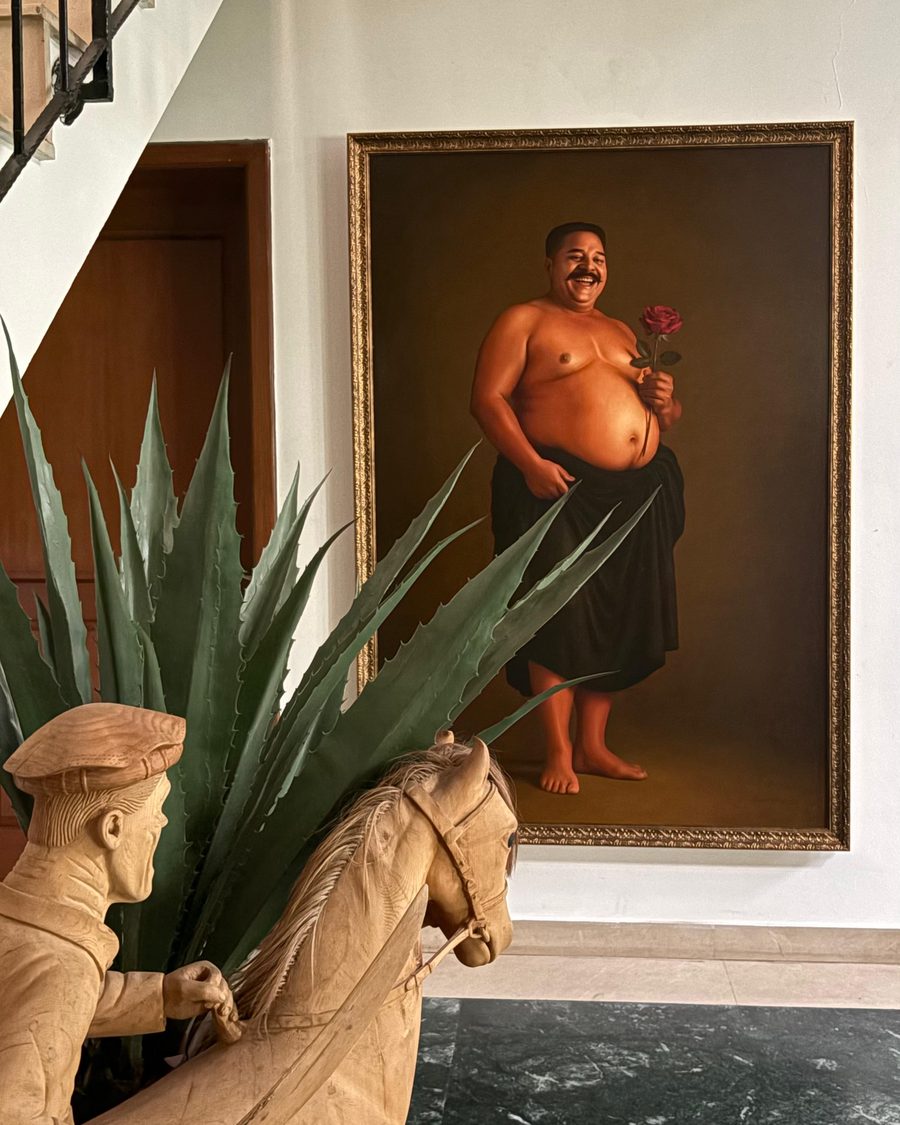 A portrait in oils above an agave and a carved horse