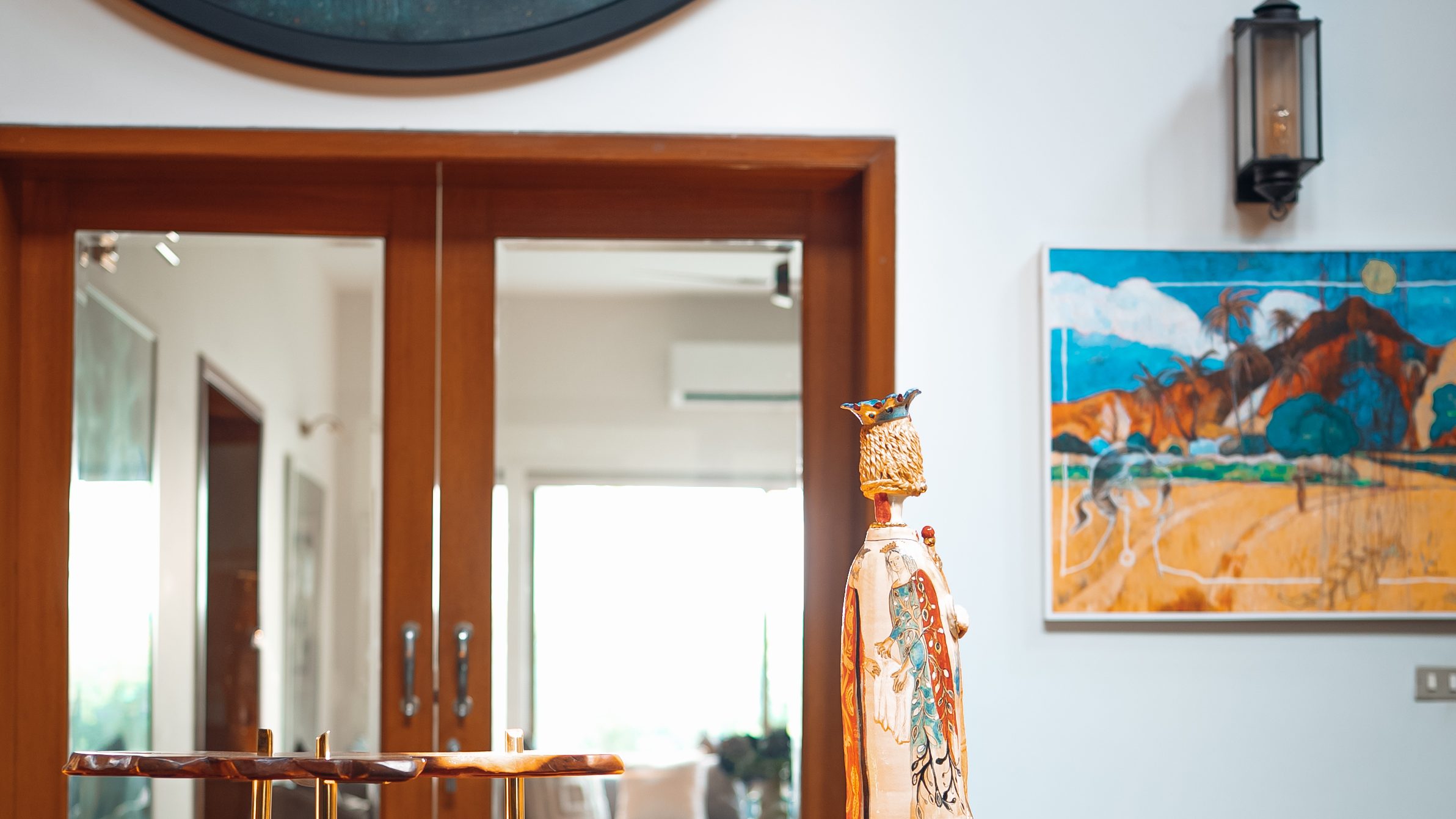 Entrance hall with a round painting, a fluted timber console and hung art