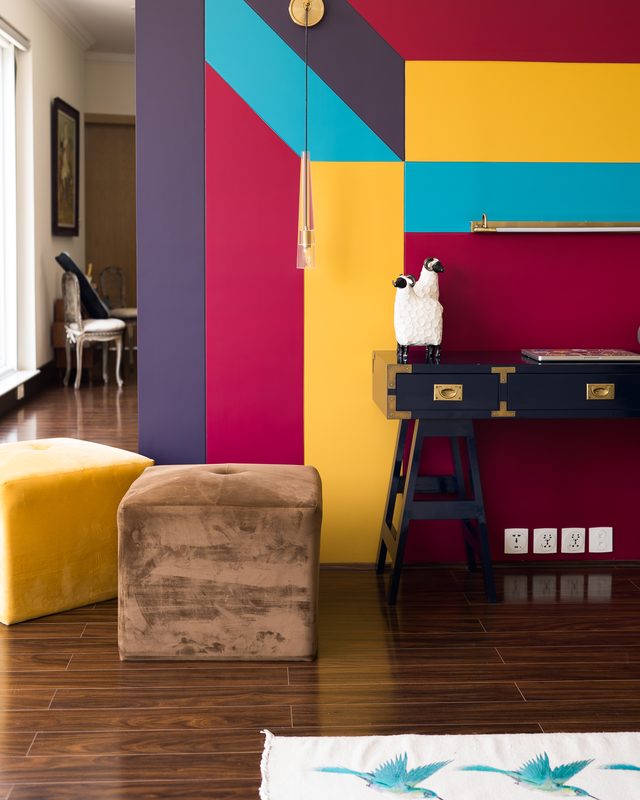 Colour-blocked wall in teal, magenta and yellow above a navy writing desk