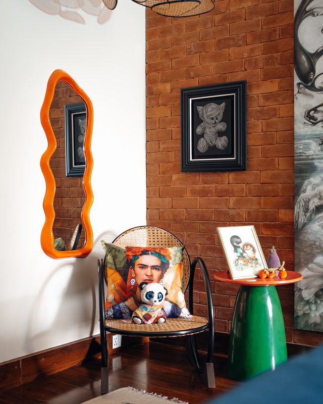 Wave-edged mirror beside a brick wall and a cane chair