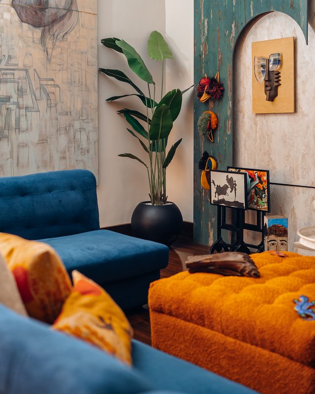 Teal arch hung with masks above a cobalt velvet sofa