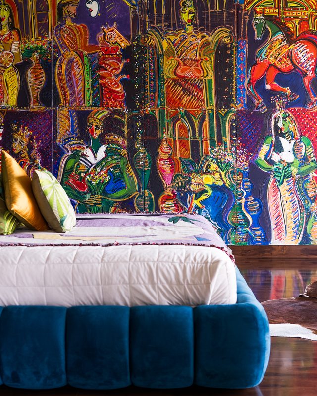 Bed beneath a four-panel painted mural
