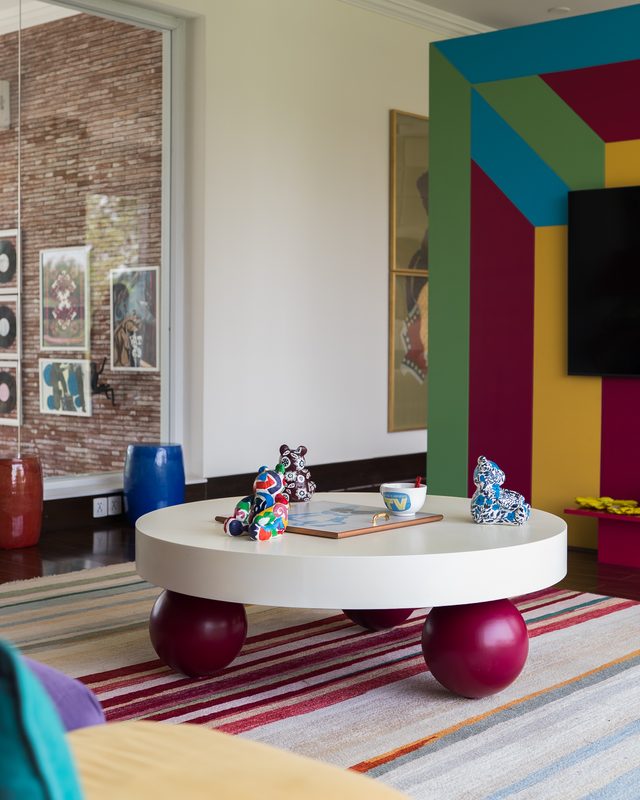Round white table on red sphere legs before a colour-blocked wall