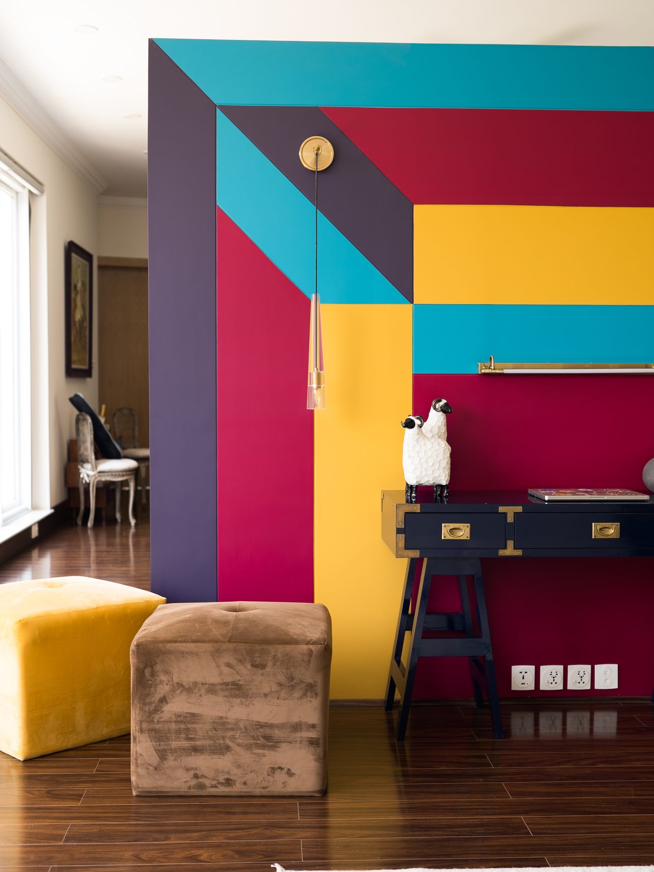 Colour-blocked wall in teal, magenta and yellow beside a round white table on red sphere legs