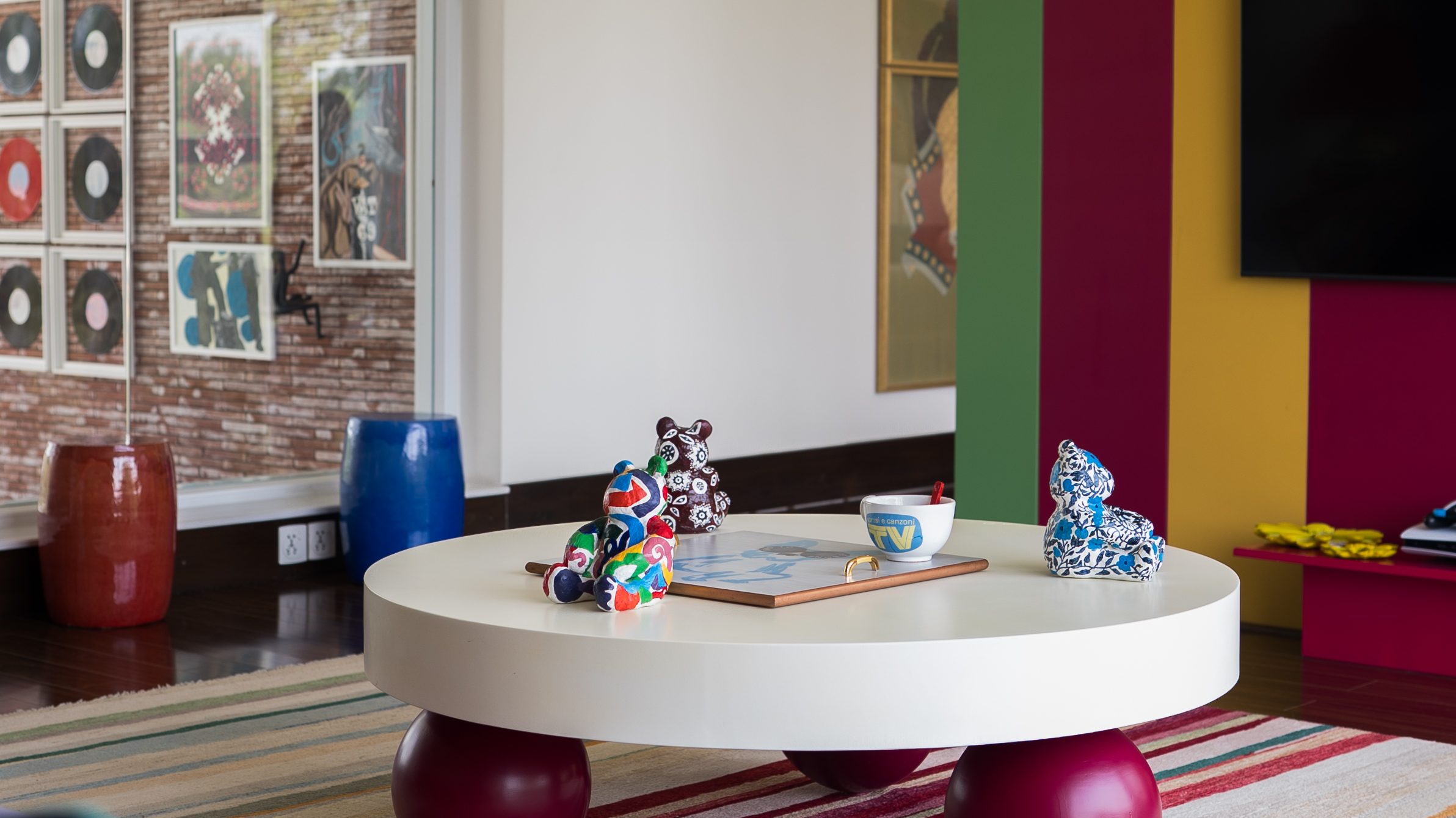 Colour-blocked wall in teal, magenta and yellow beside a round white table on red sphere legs
