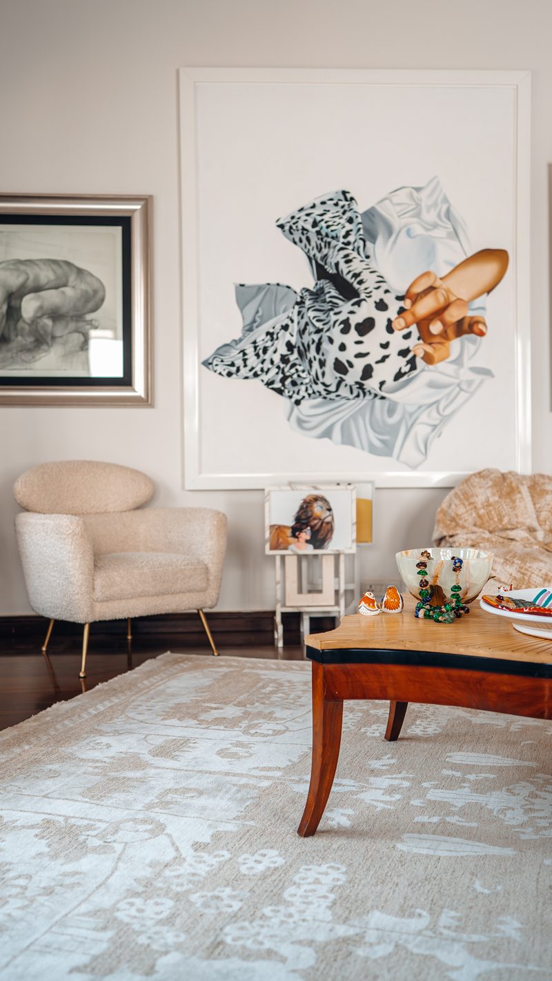 Lounge with bouclé armchairs, a carved timber table and a large painted canvas