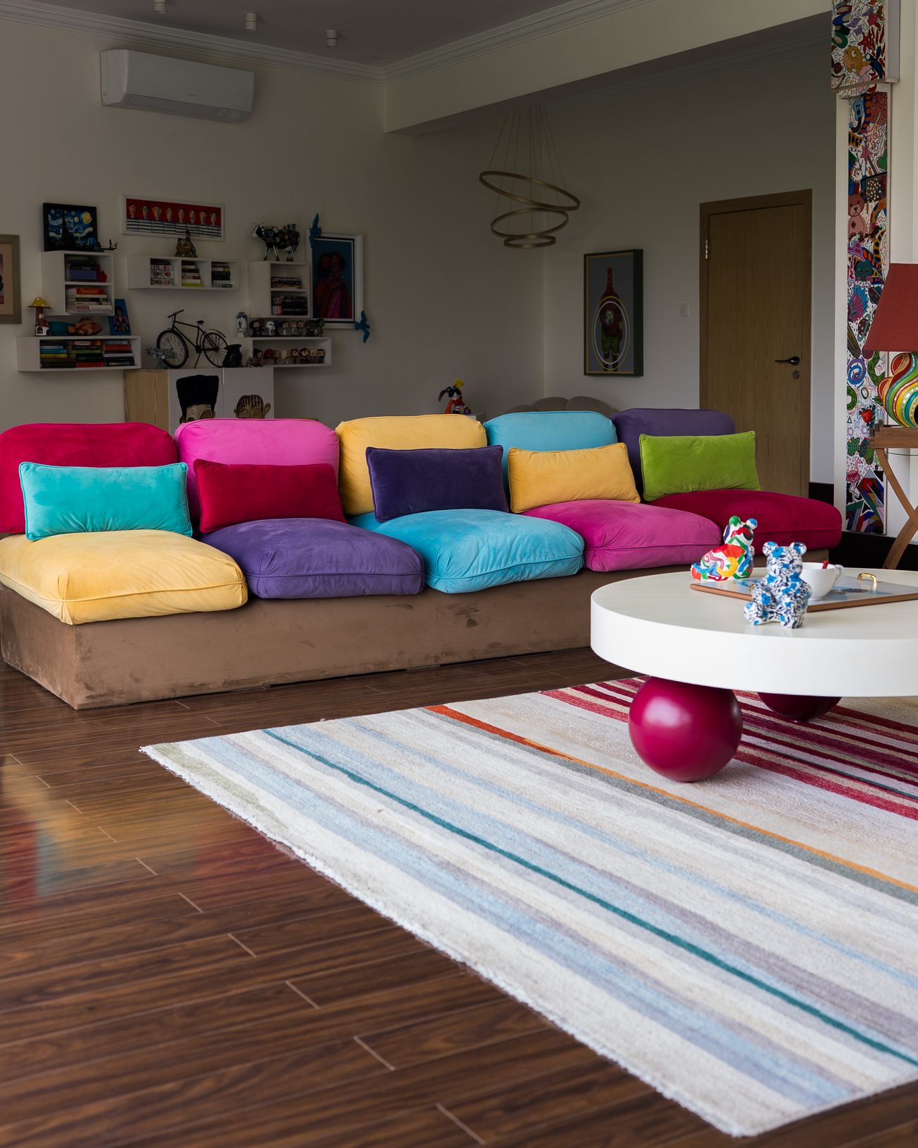 Colour-blocked wall in teal, magenta and yellow beside a round white table on red sphere legs