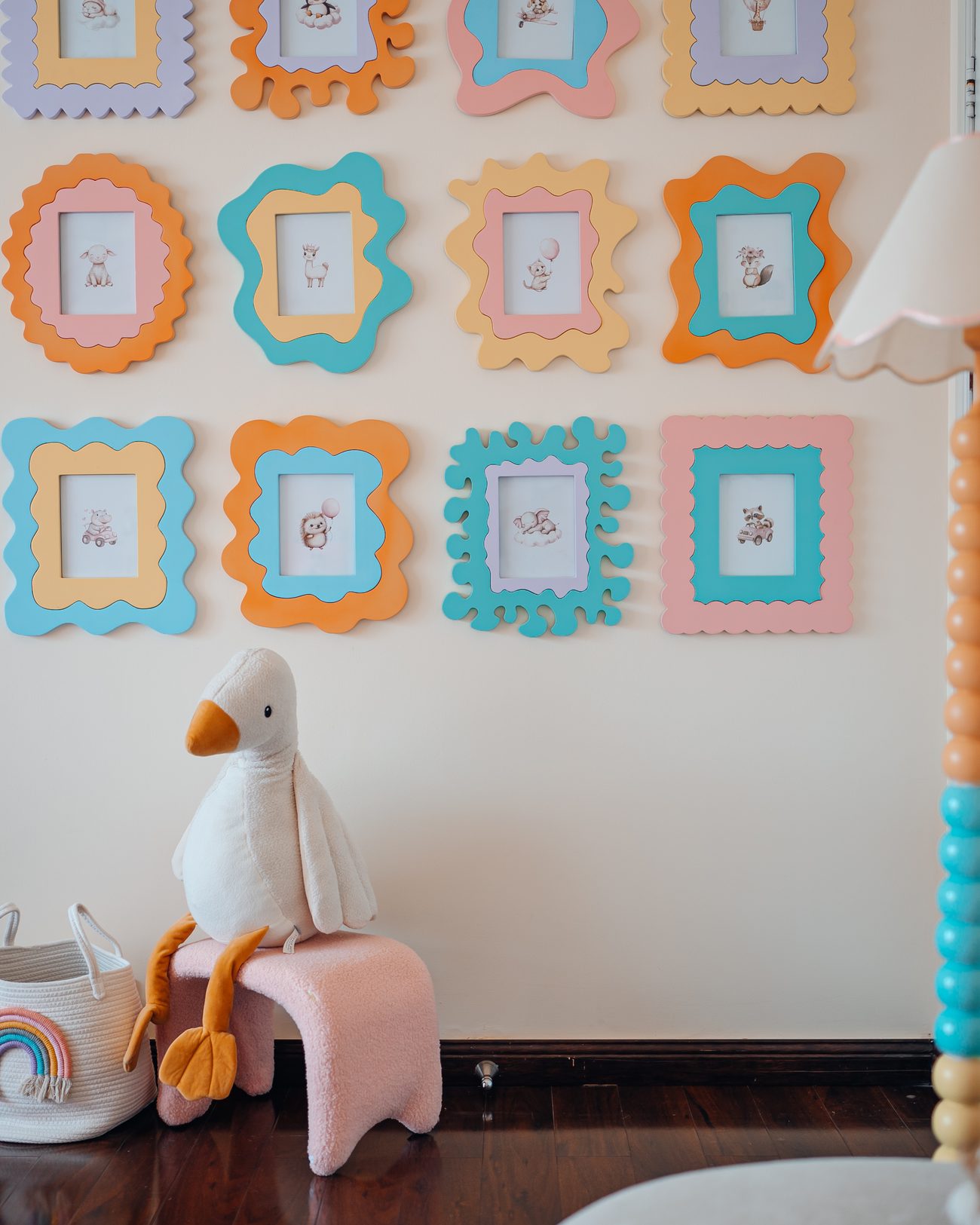 Pastel nursery with a padded rainbow, colour-blocked drawers and pompom pendant shades