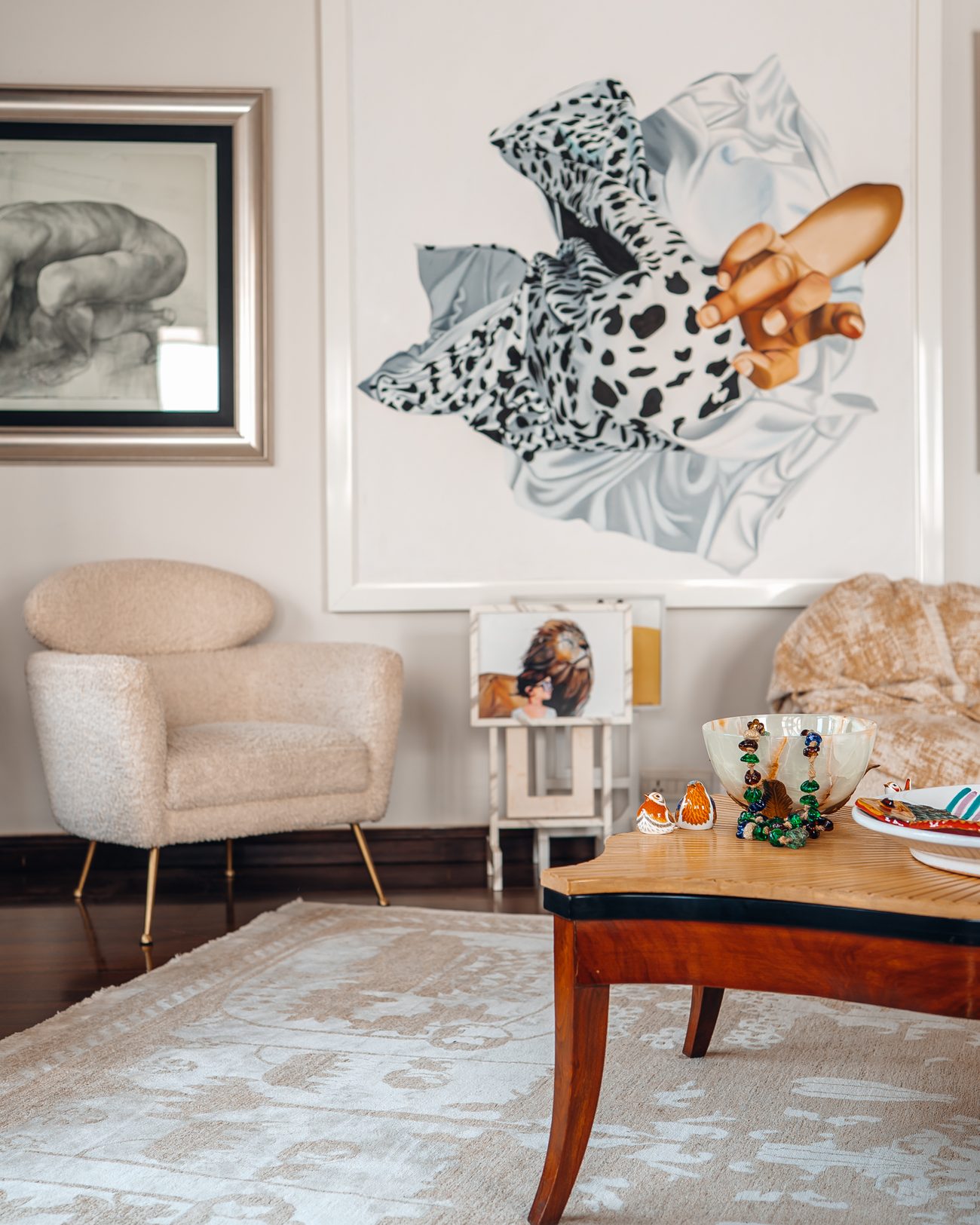 Lounge with a large painted canvas, bouclé chairs and a carved table