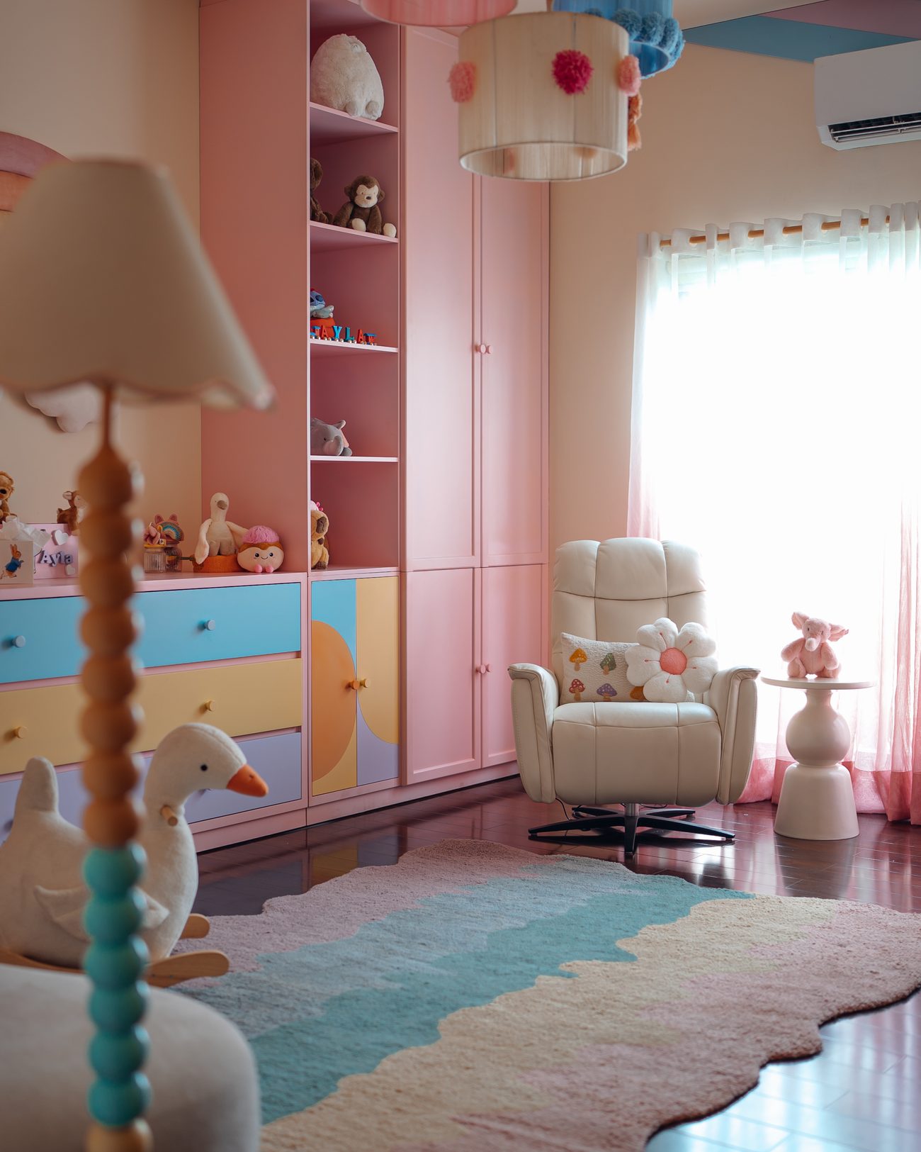 A finished pastel nursery with rainbow wall, crib and reading chair