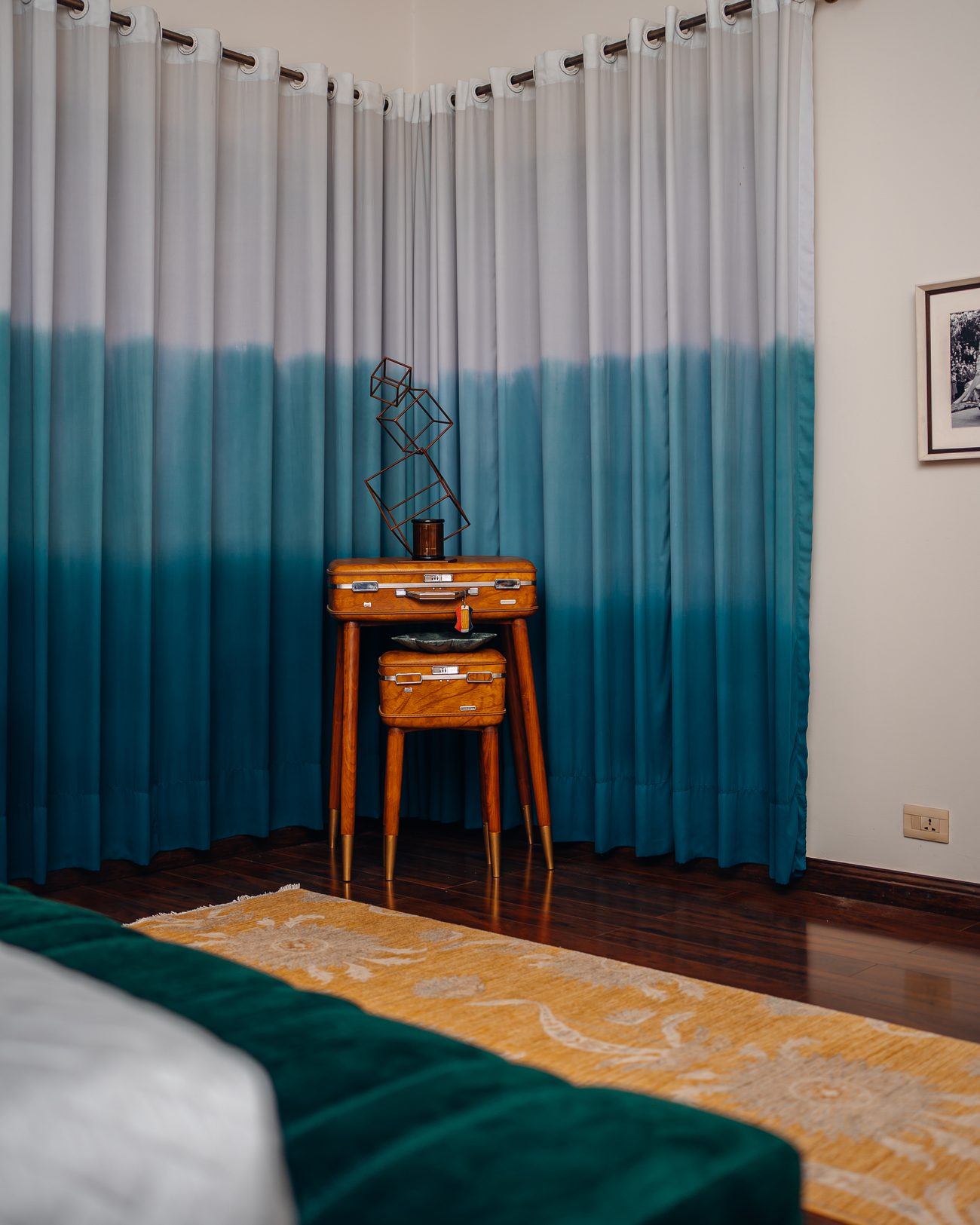 Vintage case cabinet on slender legs before teal ombré curtains