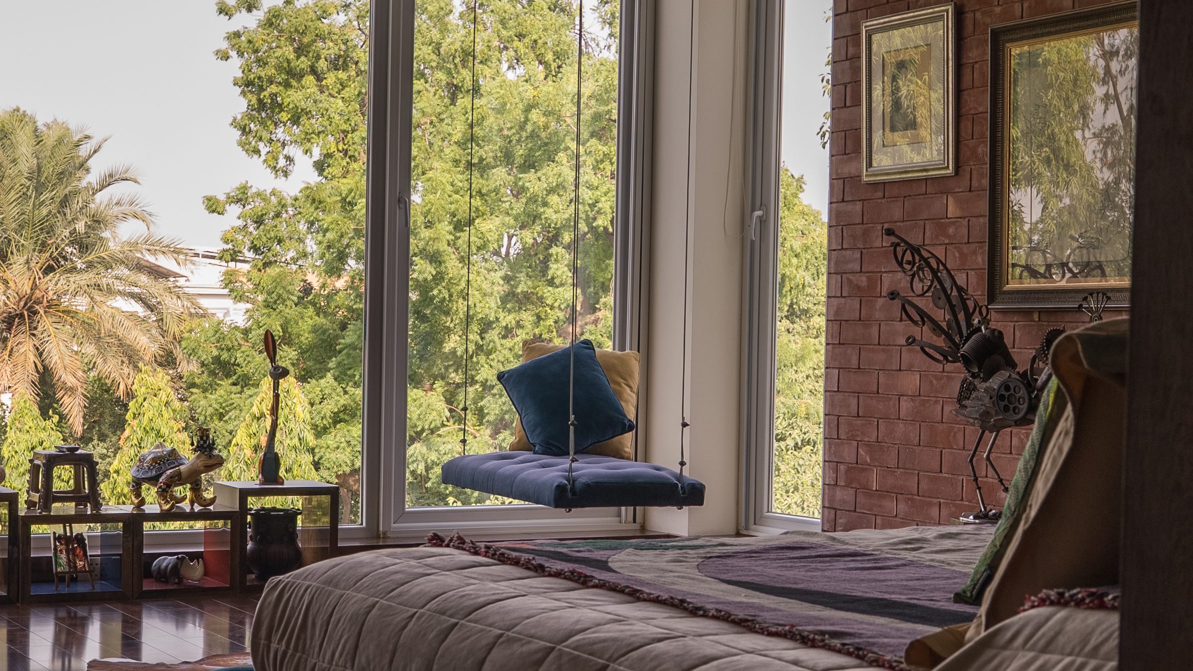 Bedroom with garden windows, a brick wall and a deep blue velvet bed